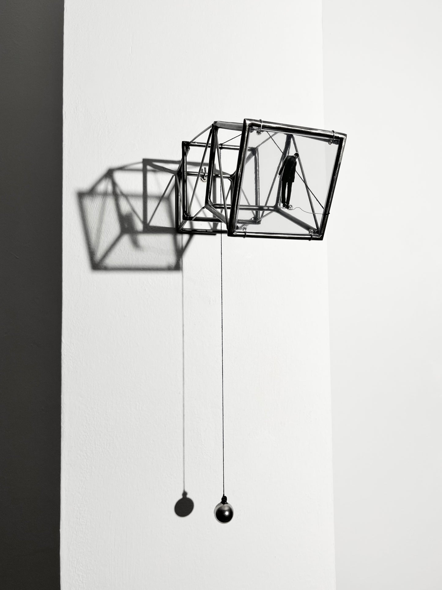 Hanging by a Thread is stylish, contemporary light and shadow sculpture, a geometric form given an asymetric twist, designed to lend any interior a quirky modernist elegance. An steel shadow artpiece depicting a man looking at his foot caught up in a thread leading to a stainless steel pendulum ball woven into the handmade structure. The image is a high quality print of an original Furst_Ori collage designed to caste a shadow within the frame.