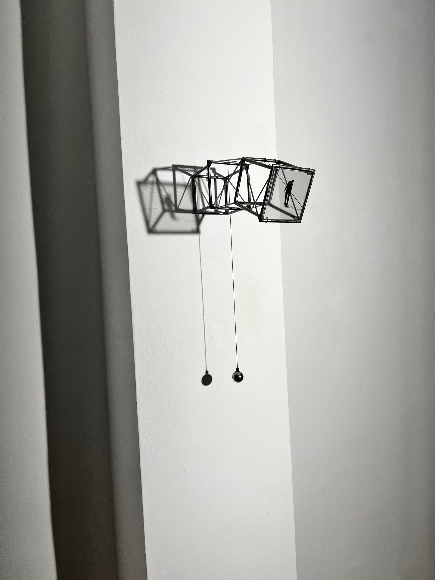 Hanging by a Thread is stylish, contemporary light and shadow sculpture, a geometric form given an asymetric twist, designed to lend any interior a quirky modernist elegance. An steel shadow artpiece depicting a man looking at his foot caught up in a thread leading to a stainless steel pendulum ball woven into the handmade structure. The image is a high quality print of an original Furst_Ori collage designed to caste a shadow within the frame.