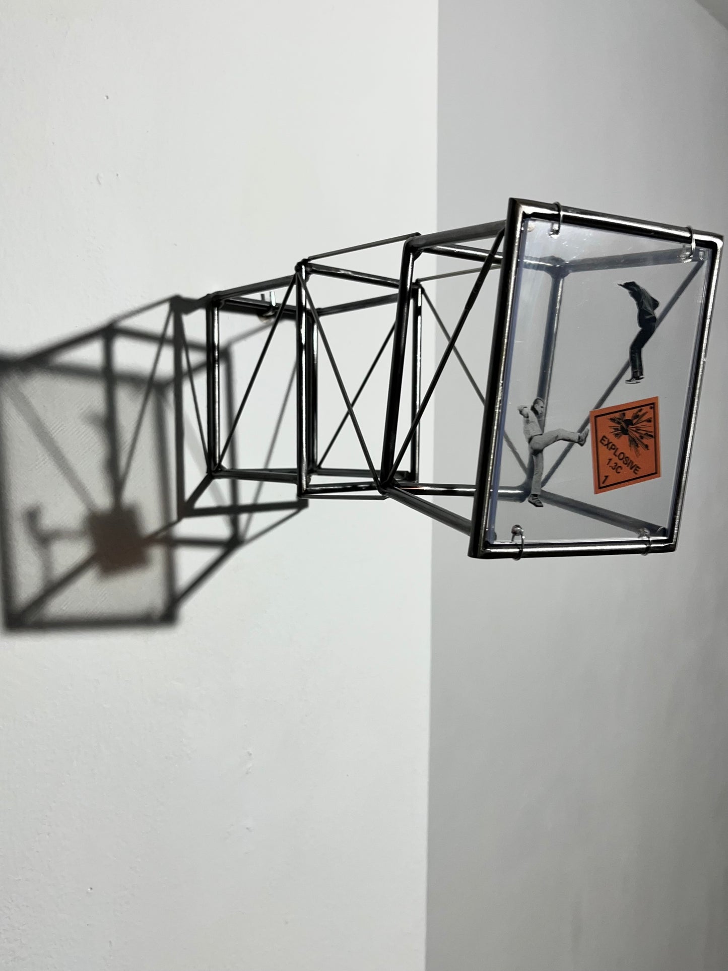 # side view of steel wall sculpture with shadow on white wall. Numbered Limited Edition Wall Sculpture Social Explosion Sign: Limited Edition Light and Shadow Sculpture Artandshadow