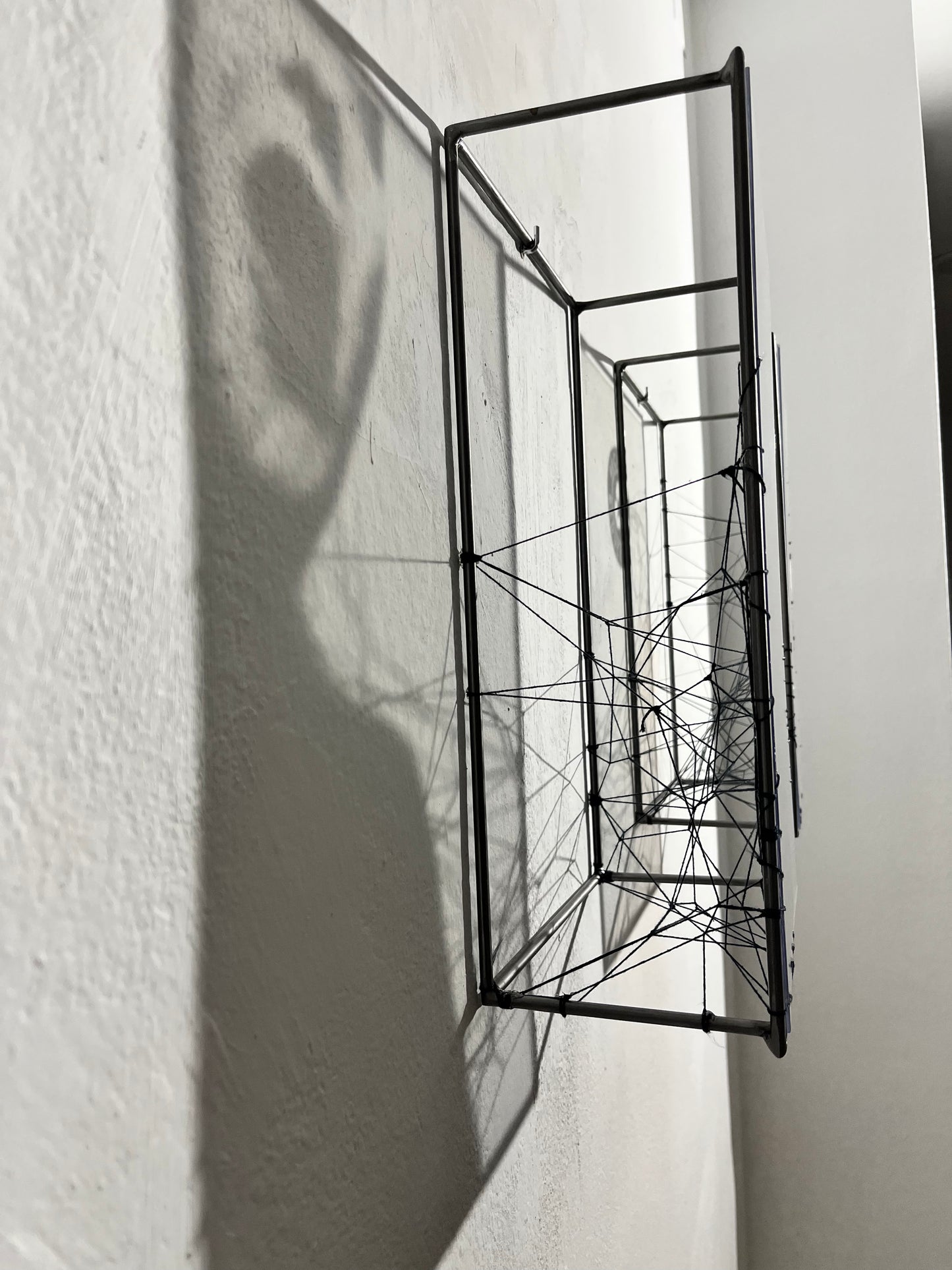 Metallic abstract sculpture casting a shadow on a white wall