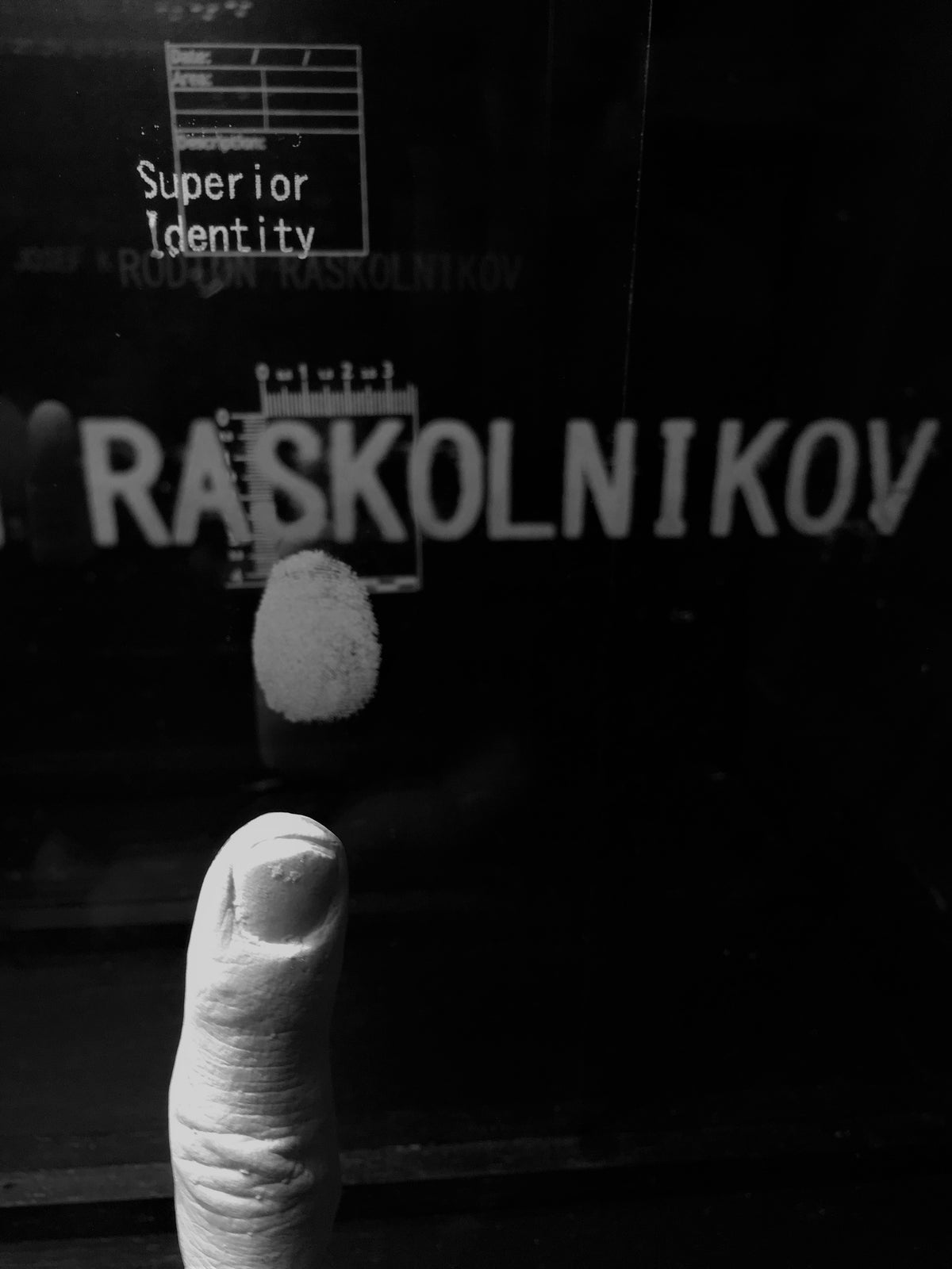 # close up of plaster cast finger with finger print on glass bearing the name Raskolnikov. Original Fine Art Sculpture Constructed Identity: Large Format Narrative Sculpture FURST_ORI